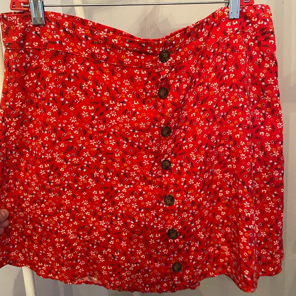 Red skirt with little blue and yellow flowers on it.